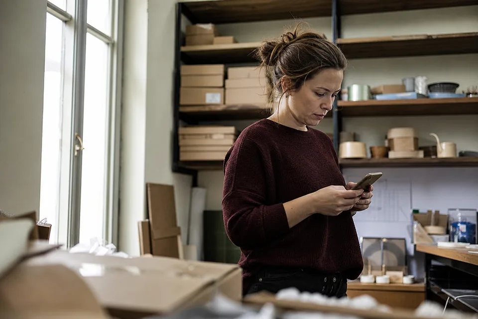 Brand owner reading a new filing alert on a phone in a stockroom